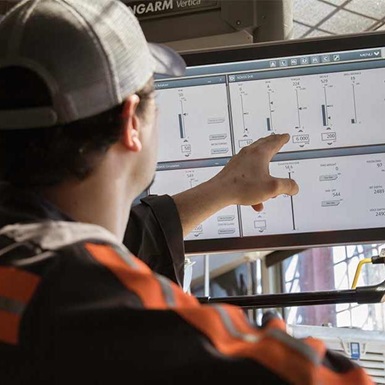 Man on in a drilling cabin points to a screen 